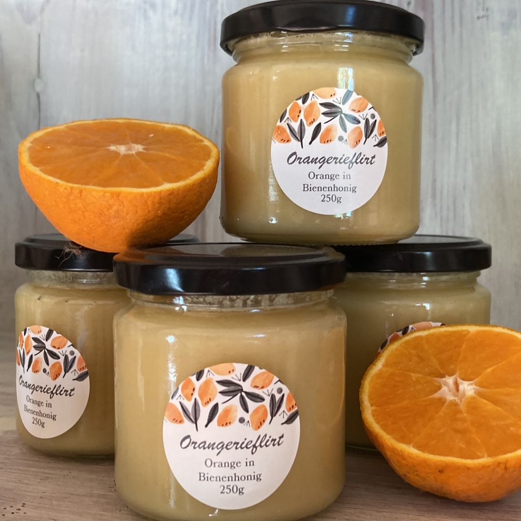 gestapelte Gläser mit Orangenflirt und eine aufgeschnittene Orange